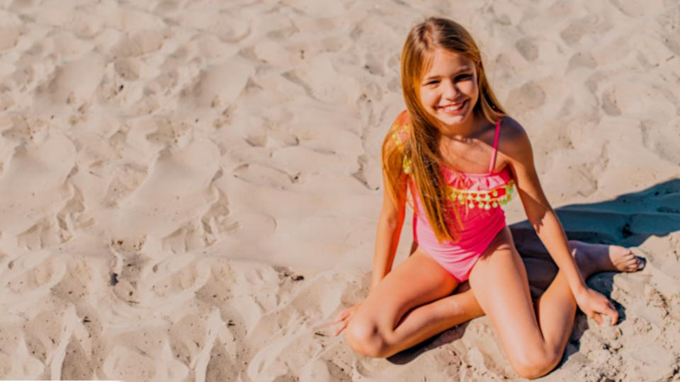 Дети на пляже. Девочка играет на песке.